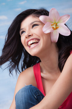 Portrait of an young beautiful laughing girl with lilies in her hair.