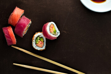 California roll sushi with chop sticks on dark background.