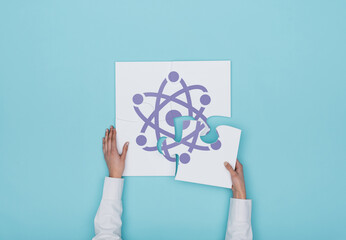 Woman completing a puzzle with atom icon, she is putting the missing piece, physics and science...