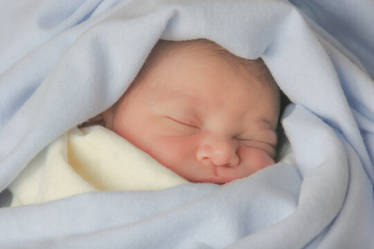 Cute sleeping baby, covered with soft cotton blankets.