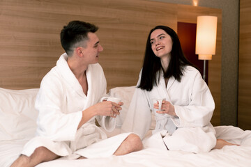 Obraz premium young couple on honeymoon in hotel room having breakfast in room drinking coffee happy lovers travel concept