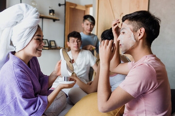 Latin LGBT Friends using Facial mask and cosmetics treatments on bed at home in Mexico, Hispanic...