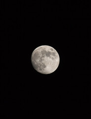 Waxing gibbous Moon, portrait orientated image with Moon isolated on black background with text or copy space.