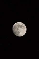 Waxing gibbous Moon, portrait orientated image in photo dimensions with Moon isolated on black background with text or copy space.