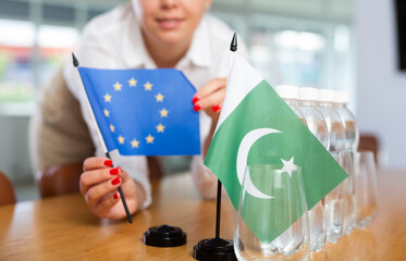 Little flag of Pakistan on table with bottles of water and flag of European Union put next to it by...
