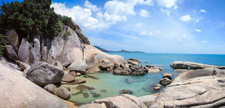 tourists exploring the rocksy coastline and clear sea pools near the grandfather rock on lamai beach on ko samui island in the guld of thailand