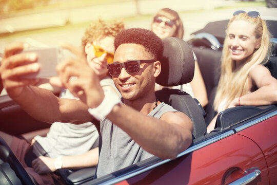 Young friends ready to vacation take a selfie in a cabriolet car