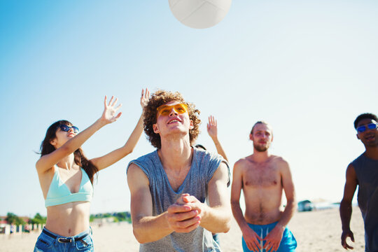 Group of happy friends playing at beach volley at the beach