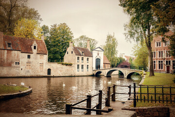 The Minnewater with bridge and entrance portal to the Bruges Beguinage De Wijngaard , Belgium, in...