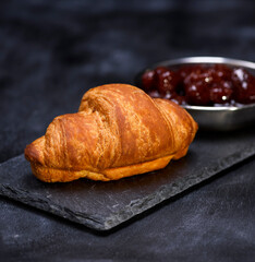 baked croissant on a black graphite background, close up