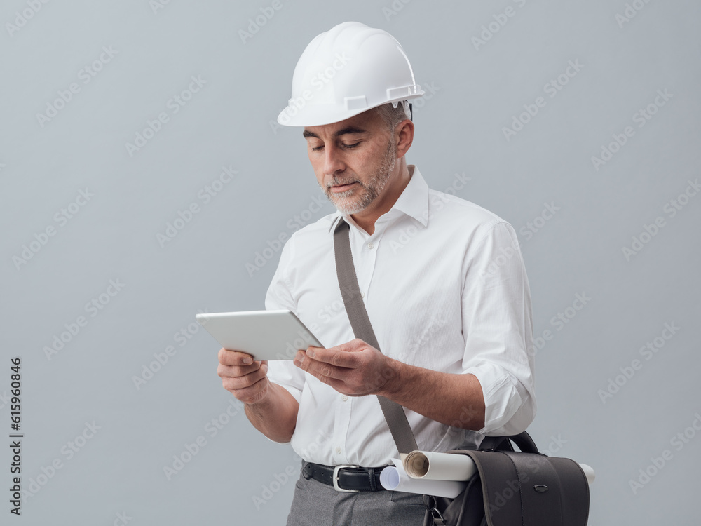 Poster construction engineer connecting with a digital tablet and using apps, he is wearing a safety helmet