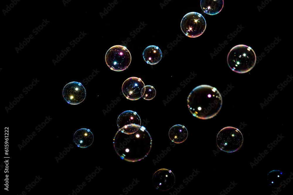 Poster beautiful multicolored soap bubbles on black background for texture and background