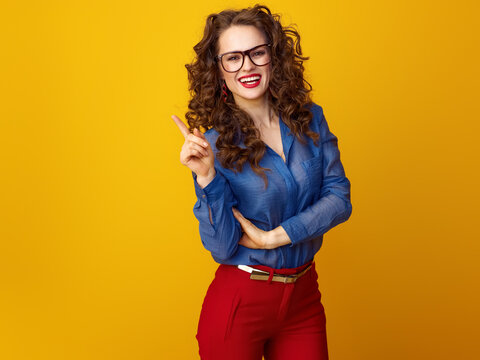 Portrait of smiling modern woman with long wavy brunette hair in glasses got idea isolated on yellow