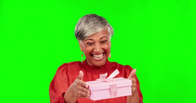 Gift, green screen and portrait of excited senior woman with a present on birthday isolated in studio background. Smile, happy and elderly female person with a surprise with happiness or celebration