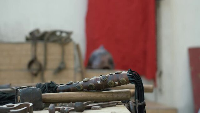 Roman soldier taking a whip from a table with torture instruments. Dolly shot, Focused detail