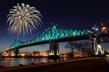 Fireworks explode over bridge, reflection in water. Montreal’s 375th anniversary. luminous...