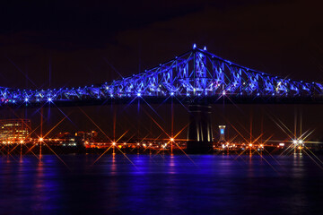 Jacques Cartier Bridge Illumination in Montreal, reflection in water. Montreal’s 375th anniversary. Luminous colorful interactive Jacques Cartier Bridge. Bridge panoramic colorful silhouette by night.