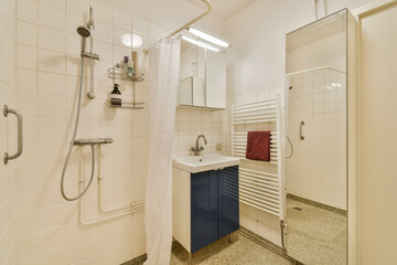 a bathroom with white tiles on the floor and blue cabinetd sink in the corner, next to an open shower stall
