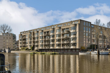 an apartment complex on the water's edge, with boats docked in the fore - image taken from across the river