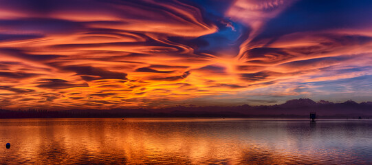 Incredible lenticular clouds in the sky during a sunset over the Varese lake