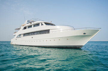 Large private luxury motor yacht boat sailing out on a tropical sea