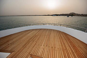 View over the bow of a large luxury motor yacht on tropical open ocean at sunset