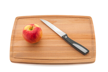 Ripe red juicy apple and knife on a cutting board made of dark wood.