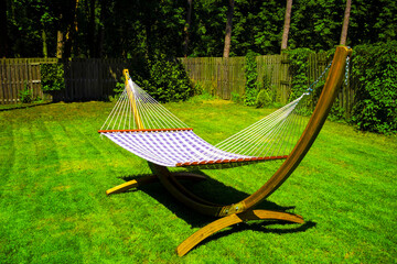 Sunny wooden hammock standing in green garden.