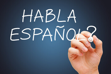 Hand writing question Habla Espanol - Speak Spanish with white marker on dark blue background.