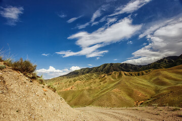 rural road through green meadows on rolling hills. hiking through carpathian rural area. mountain landscape in summer on a sunny day. ridge in the distance