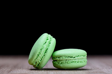 Two green macaroons on wooden table, close up