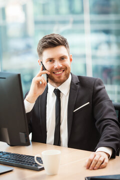 Young businessman at the office sitting at his desk and talking on a phone