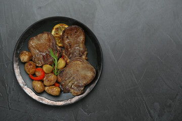 Tasty beef tongue pieces, rosemary, lemon and potatoes on grey table, top view. Space for text