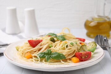 Delicious pasta primavera with tomatoes, basil and broccoli on white table, closeup