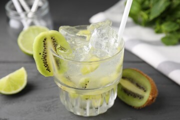 Glass of refreshing drink and cut kiwi on gray table, closeup