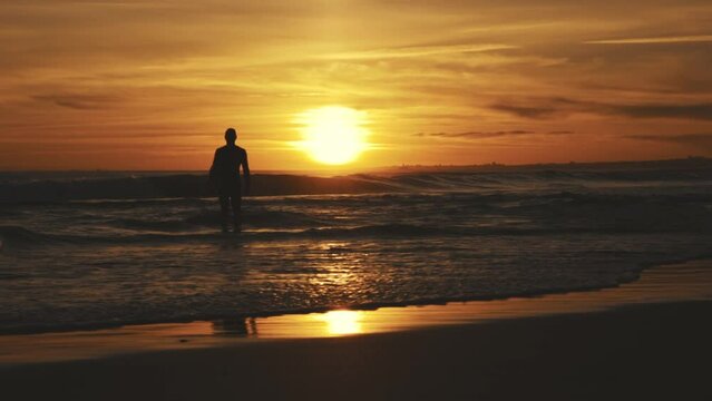 Silhouette of athletic surfer at sunset in sea