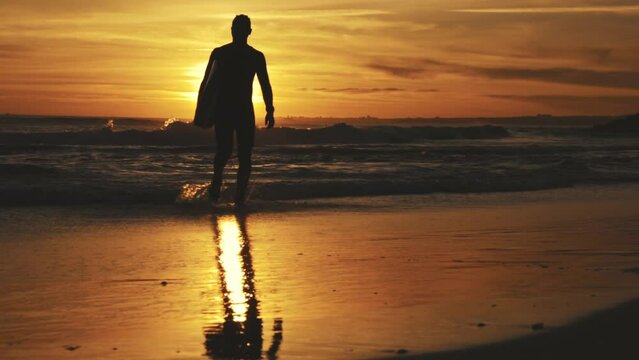 Silhouette of surfer at background of sunset