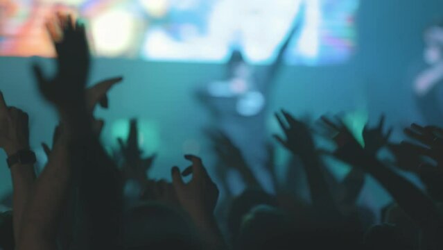 People in crowd waving their hands at live concert