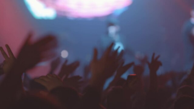 People in crowd swing arms to sides at live show