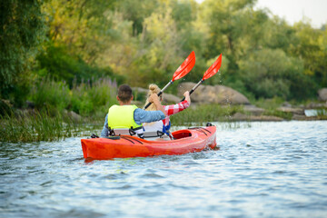 Young Happy Couple Paddling Kayak on the Beautiful River or Lake