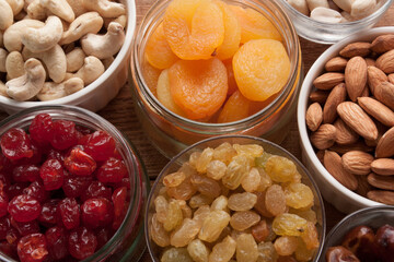 Nuts and dried fruits assortment dried apricots, dried cherries, raisins, almonds, cashews, date fruits, peanuts on wooden table. Top view.