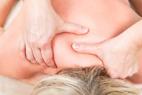 Masseur makes a massage of the cervical spine with bold hands