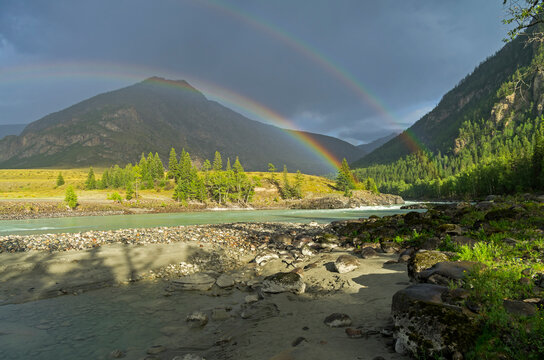 Rainbow over the river. Argut River merger with Katun. Altai Mountains, Russia. August.