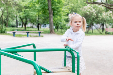 Fototapeta na wymiar Little girl spins the carousel to ride at the playground