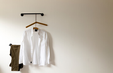 White shirt and pants hanging against white wall