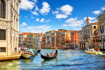 Venice, Italy. Gondolas with tourists floating by Grand Canal among antique buildings and traditional italian Venetian architecture. Sunny day with blue sky and clouds. © Designpics