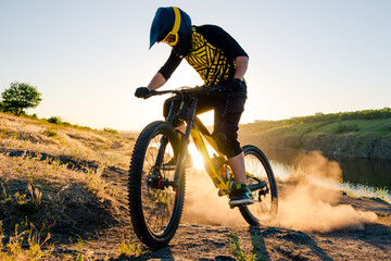 Professional Cyclist Riding the Downhill Mountain Bike on the Summer Rocky Trail at the Evening. Extreme Sport and Enduro Cycling Concept.