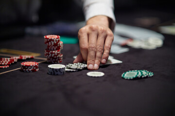 Dealer or croupier shuffles poker cards in a casino on the background of a table, chips. Concept of...