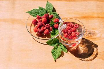 Ripe red raspberry drink in a transparent glass wooden background, summer seasonal food and refreshing drinks