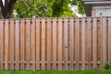 Foto op Plexiglas Nice new wooden fence around house. Wooden fence with green lawn. Street photo © Elena_Alex